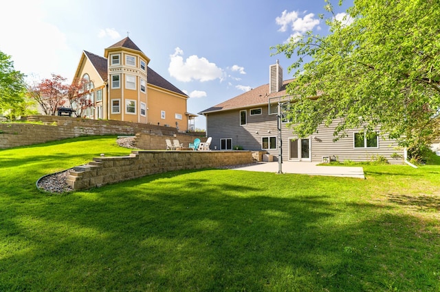 rear view of house featuring a patio, a chimney, and a yard