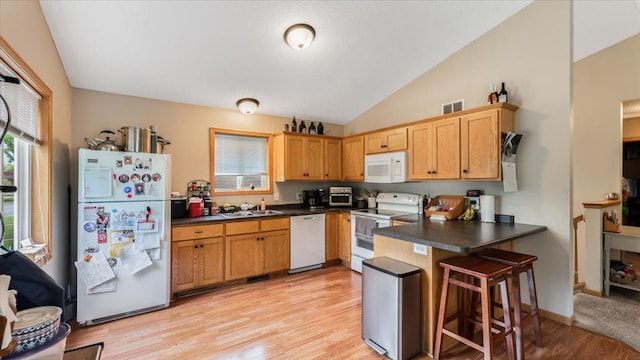 833 19th Ave N, Saint Cloud, MN 56303 - kitchen featuring white appliances, a peninsula, lofted ceiling, dark countertops, and light wood-style floors