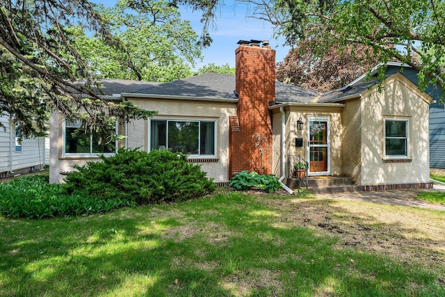 view of front of house featuring a chimney, a front yard, stucco siding, and roof with shingles