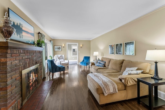 living room featuring dark wood-style flooring, a brick fireplace, baseboards, and ornamental molding