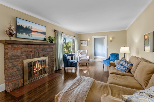living area featuring baseboards, a brick fireplace, and wood finished floors