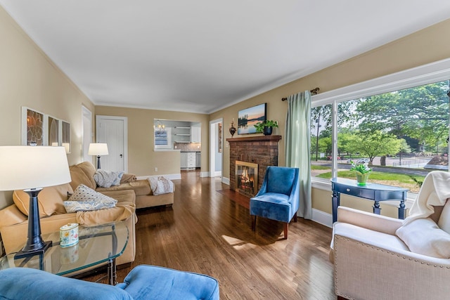 living area featuring wood finished floors, a brick fireplace, and baseboards