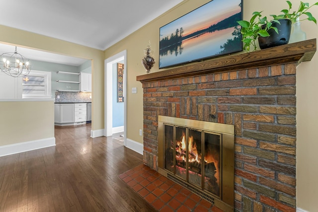 living room with a brick fireplace, hardwood / wood-style flooring, baseboards, and a chandelier