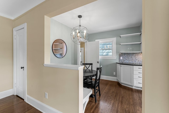 dining area featuring dark wood-style floors, a chandelier, and baseboards