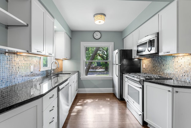 kitchen with stainless steel appliances, a sink, baseboards, dark wood finished floors, and white cabinetry