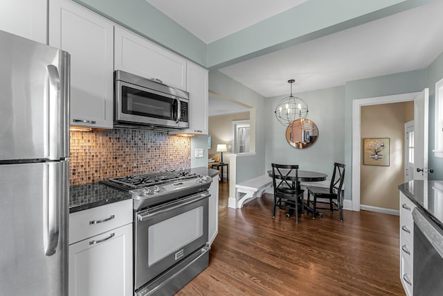 kitchen with appliances with stainless steel finishes, backsplash, dark wood-style floors, white cabinets, and a chandelier