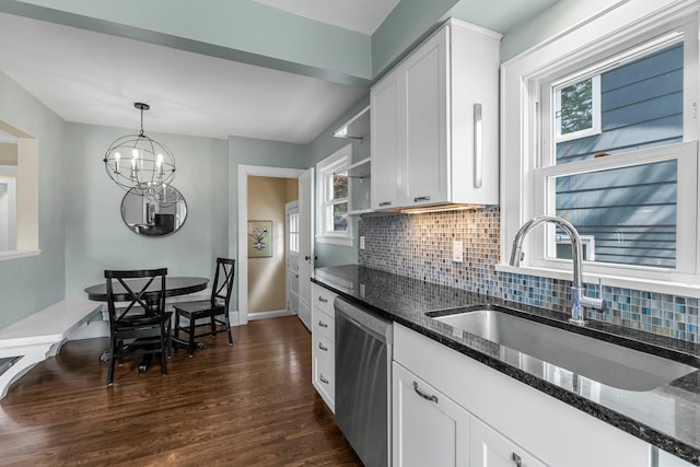 kitchen with stainless steel dishwasher, a sink, white cabinetry, dark stone counters, and tasteful backsplash