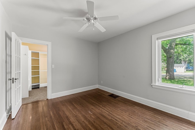 unfurnished room featuring dark wood-style floors, baseboards, and ceiling fan