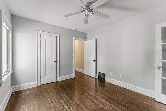 unfurnished bedroom featuring wood finished floors, multiple windows, and baseboards