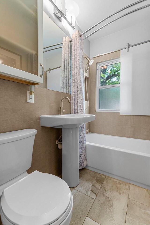 full bathroom with toilet, tile walls, and shower / bathtub combination with curtain