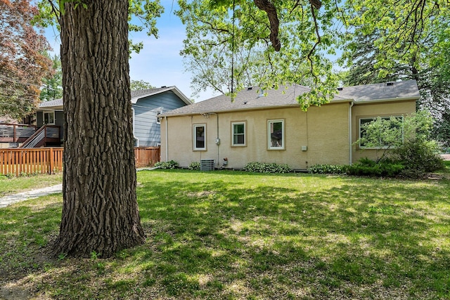 back of house with stucco siding, central AC, and roof with shingles