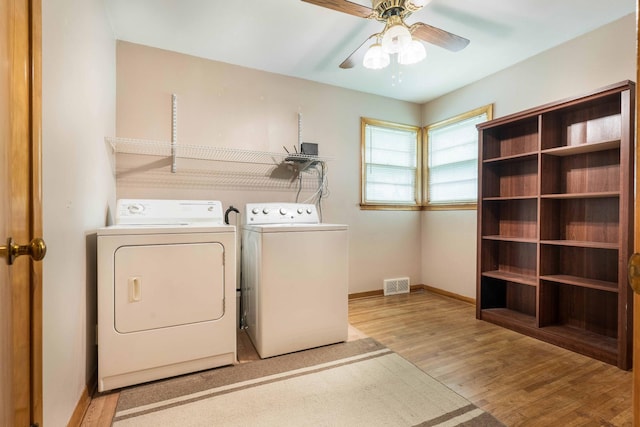 laundry room featuring washing machine and clothes dryer, wood finished floors, a ceiling fan, and baseboards