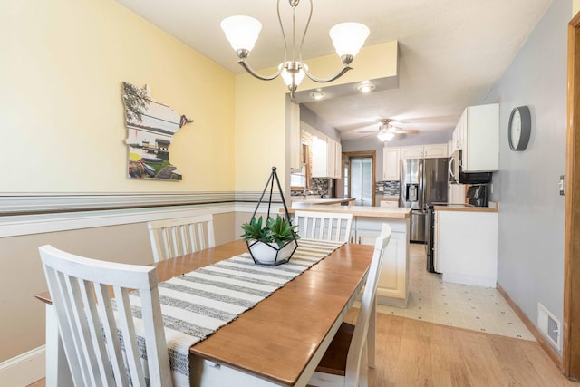 dining area with a chandelier, baseboards, and a ceiling fan