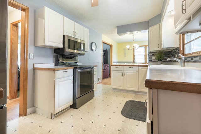kitchen featuring stainless steel appliances, light floors, a chandelier, white cabinets, and decorative backsplash