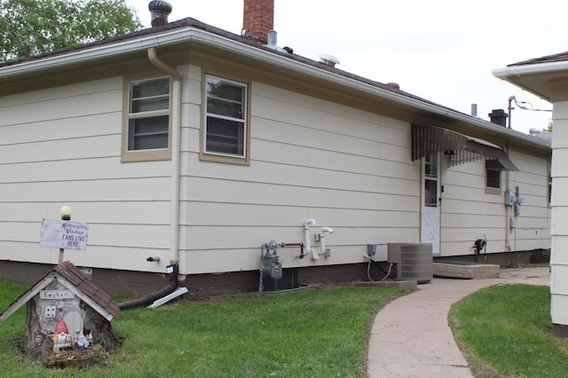 view of property exterior with cooling unit, a yard, and a chimney