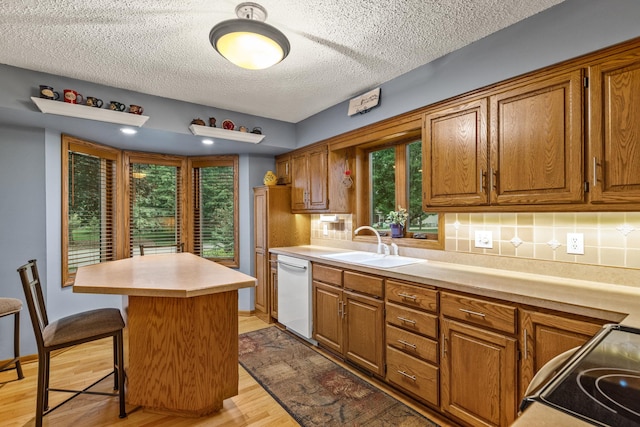 480 Suzanne Ave, Shoreview, MN 55126 - kitchen featuring dishwasher, brown cabinetry, a center island, and a textured ceiling