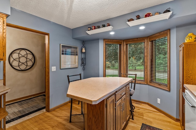 480 Suzanne Ave, Shoreview, MN 55126 - kitchen featuring light wood-style floors, stainless steel dishwasher, a kitchen island, light countertops, and a textured ceiling