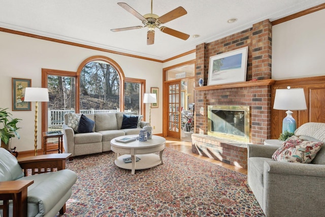 1438 Kings Wood Rd, Eagan, MN 55122 - living room featuring wood finished floors, ornamental molding, a ceiling fan, a brick fireplace, and baseboards