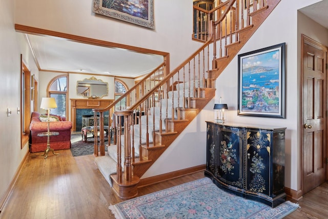 1438 Kings Wood Rd, Eagan, MN 55122 - stairs featuring a fireplace, baseboards, wood finished floors, and crown molding