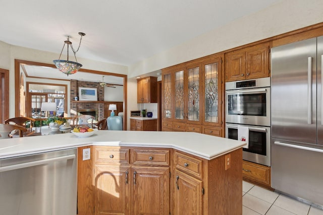 1438 Kings Wood Rd, Eagan, MN 55122 - kitchen featuring appliances with stainless steel finishes, brown cabinets, a brick fireplace, and light countertops