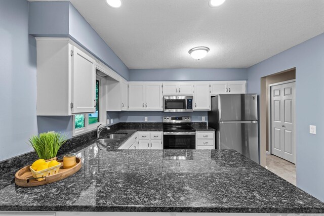 824 96th Ln NE, Blaine, MN 55434 - kitchen featuring stainless steel appliances, a peninsula, white cabinets, dark stone counters, and a textured ceiling