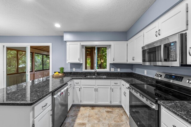 824 96th Ln NE, Blaine, MN 55434 - kitchen featuring stainless steel appliances, a peninsula, white cabinetry, healthy amount of natural light, and a textured ceiling