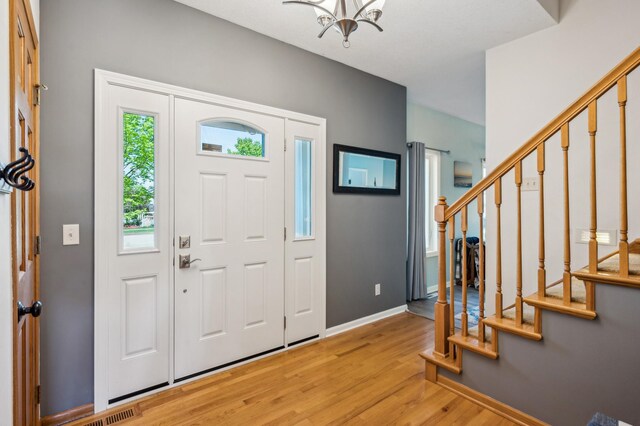 1005 Hope Ave, Jordan, MN 55352 - entrance foyer featuring light wood-type flooring, a chandelier, stairs, and baseboards