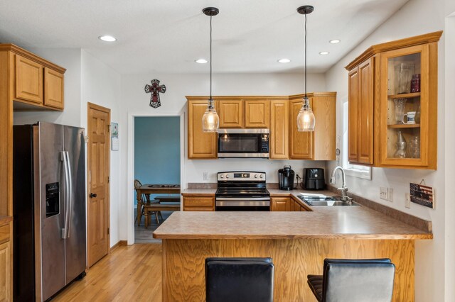 1005 Hope Ave, Jordan, MN 55352 - kitchen featuring stainless steel appliances, a sink, a peninsula, light wood-type flooring, and pendant lighting
