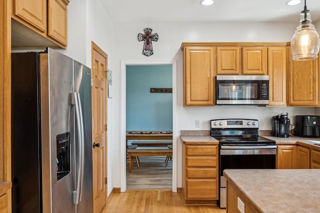 1005 Hope Ave, Jordan, MN 55352 - kitchen with appliances with stainless steel finishes, light countertops, light wood-style floors, recessed lighting, and hanging light fixtures