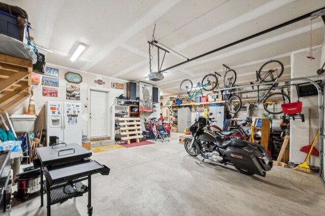 1005 Hope Ave, Jordan, MN 55352 - garage with a garage door opener and white refrigerator with ice dispenser