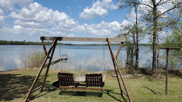 view of grassy yard featuring a water view and a dock