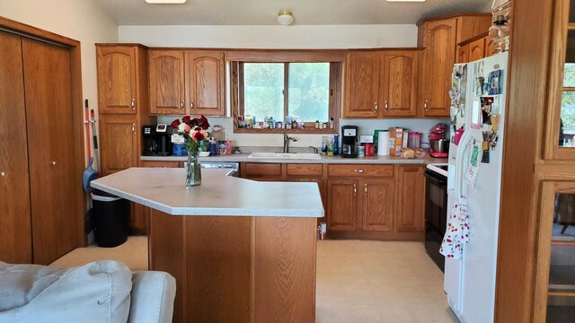 kitchen with a sink, brown cabinets, light countertops, and range with electric stovetop
