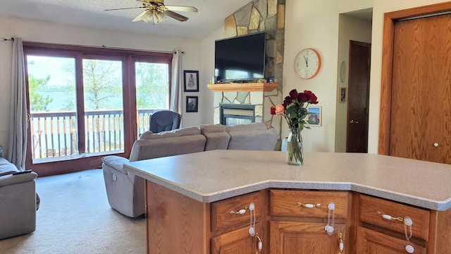kitchen featuring vaulted ceiling, a ceiling fan, open floor plan, light countertops, and light colored carpet