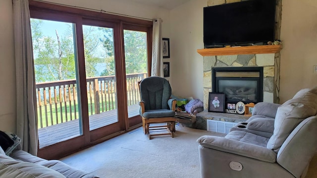 living area with carpet flooring and a stone fireplace
