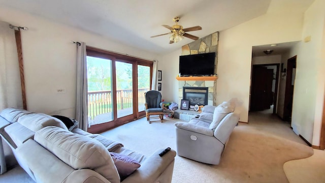 living area with vaulted ceiling, a ceiling fan, light colored carpet, and a stone fireplace