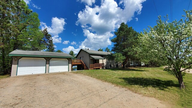 view of front of property with a front lawn, a wooden deck, and a detached garage