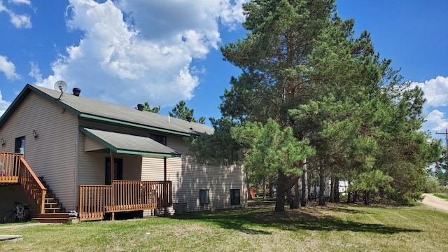 back of property with a yard, a wooden deck, and central AC unit