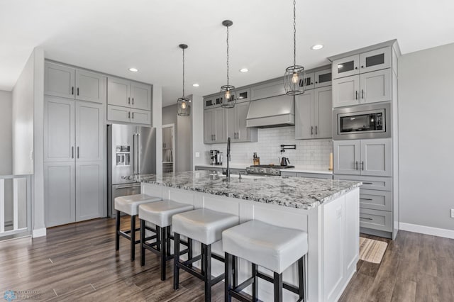 1991 69th Ave S, Fargo, ND 58104 - kitchen with stainless steel appliances, gray cabinetry, custom range hood, decorative backsplash, and dark wood-type flooring