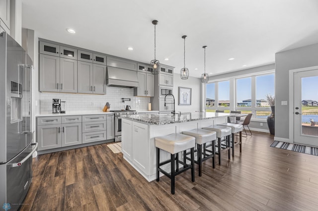 1991 69th Ave S, Fargo, ND 58104 - kitchen with stainless steel appliances, custom exhaust hood, gray cabinetry, a kitchen bar, and glass insert cabinets