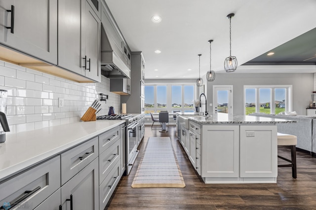 1991 69th Ave S, Fargo, ND 58104 - kitchen featuring stainless steel range, healthy amount of natural light, decorative backsplash, a breakfast bar, and recessed lighting