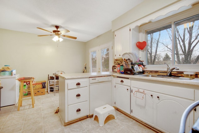 kitchen featuring white dishwasher, a sink, healthy amount of natural light, and a peninsula
