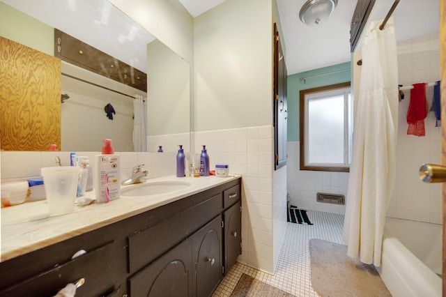 full bath with tile walls, tile patterned flooring, vanity, a wainscoted wall, and shower / bath combo