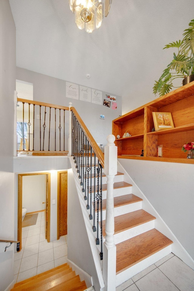 stairs with tile patterned flooring, a chandelier, and baseboards