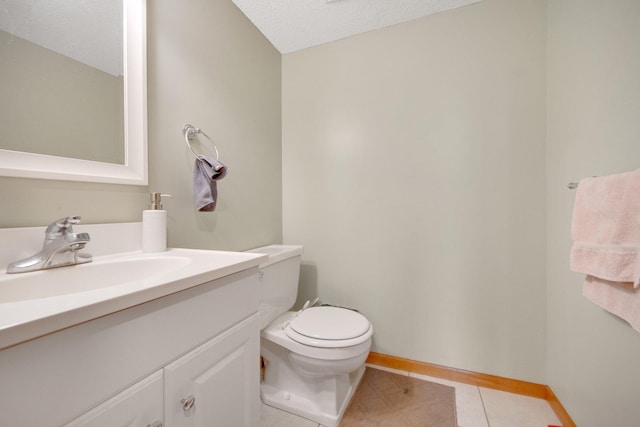 half bathroom featuring tile patterned flooring, vanity, toilet, and a textured ceiling