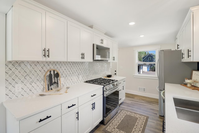 kitchen with appliances with stainless steel finishes, baseboards, white cabinetry, and recessed lighting
