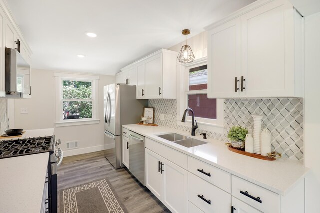 kitchen with appliances with stainless steel finishes, a sink, white cabinets, light wood finished floors, and light countertops