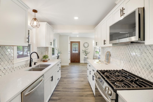 kitchen featuring stainless steel appliances, a sink, recessed lighting, wood finished floors, and white cabinetry