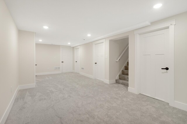 finished below grade area with stairway, recessed lighting, light carpet, and baseboards