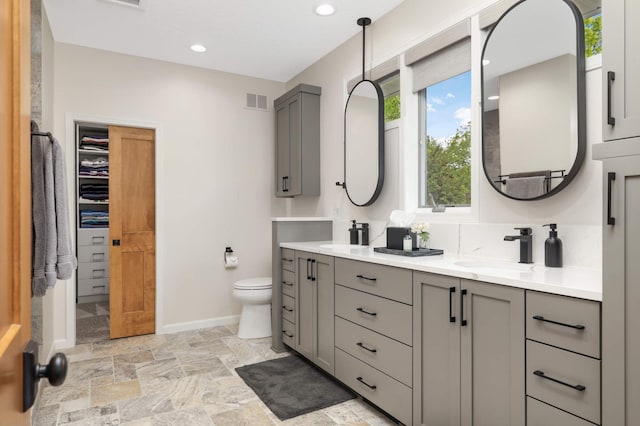 14575 268th Ave NW, Zimmerman, MN 55398 - bathroom with double vanity, baseboards, toilet, stone finish floors, and a walk in closet