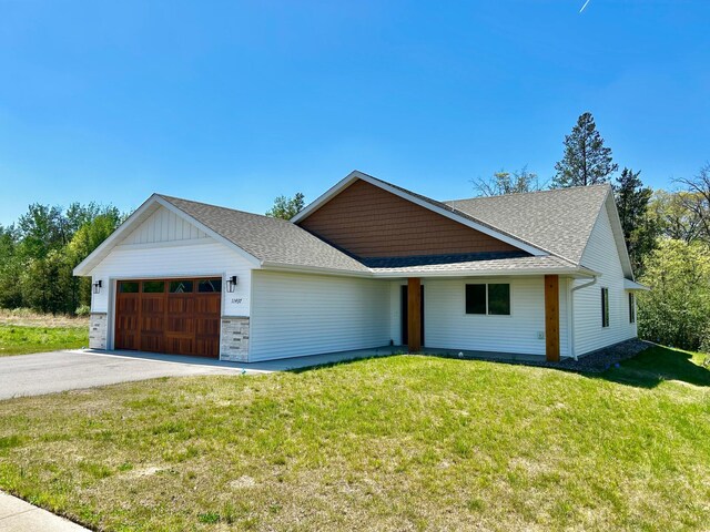 view of front facade featuring an attached garage, roof with shingles, asphalt driveway, and a front lawn